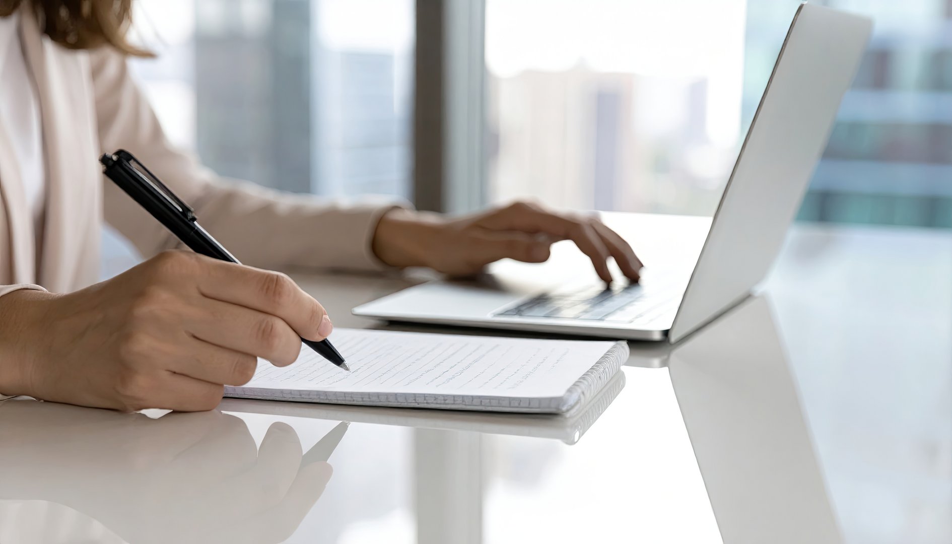 Woman's hands writing notes near laptop, blurred office view Koordynacja, zarządzanie infrastrukturą
