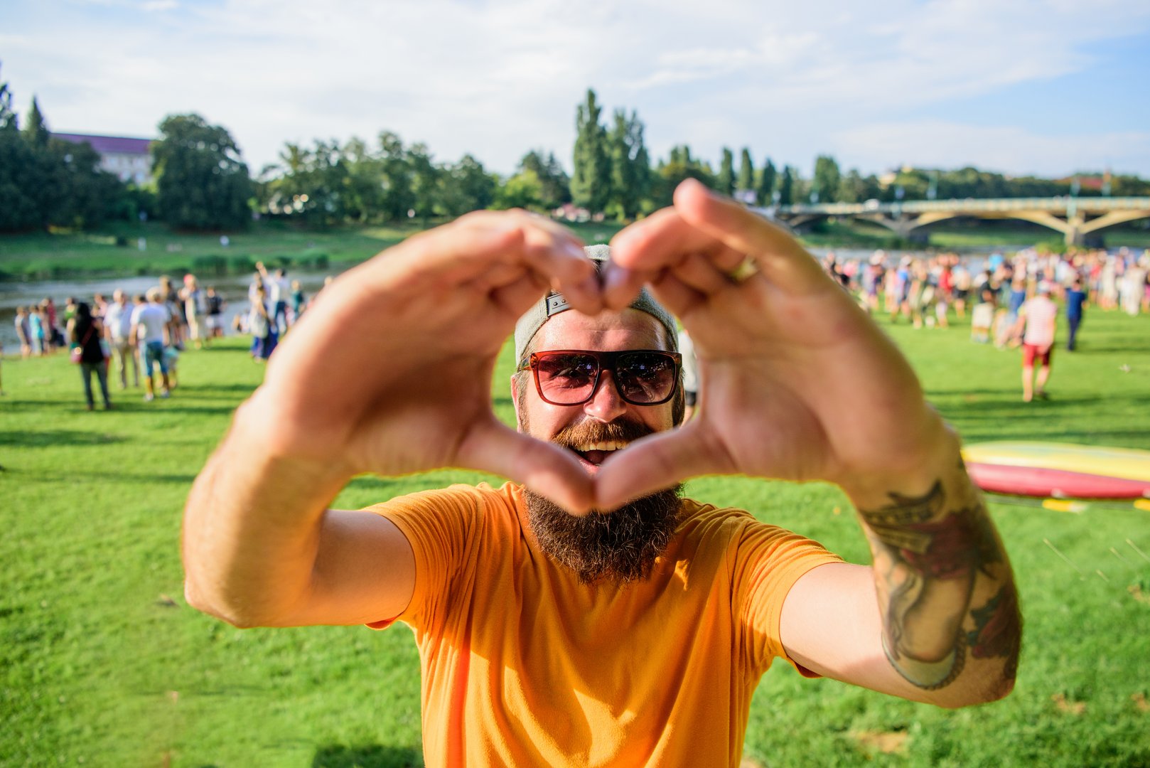 Hipster happy celebrate event picnic fest or festival. Cheerful fan love summer fest. Man bearded hipster in front of crowd people show heart gesture riverside background. Urban event celebration Imprezy firmowe, rodzinne